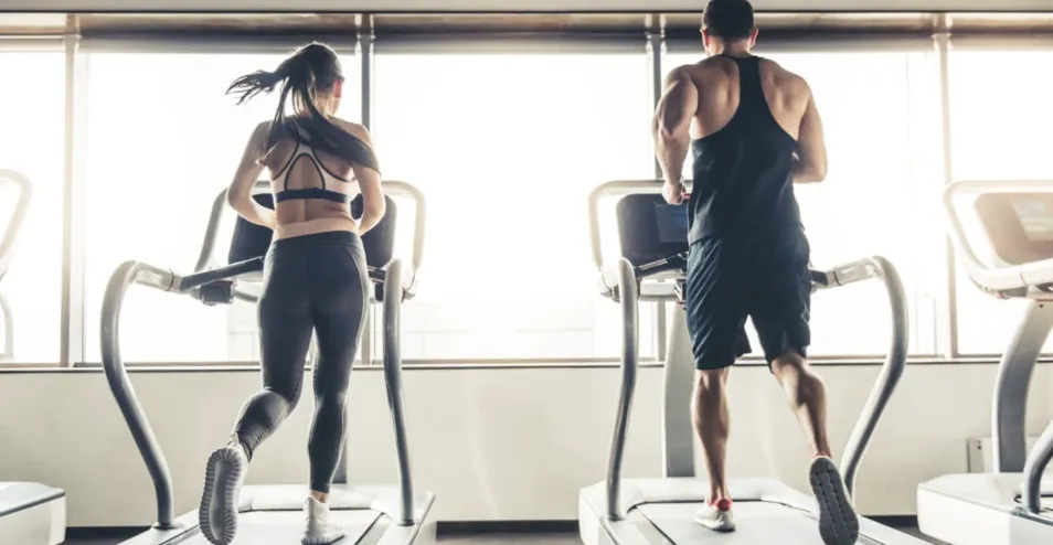 Couple walking on two treadmills to lose weight fast